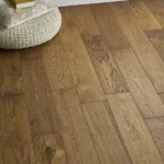 Wide view of oak wood flooring with white baseboard.